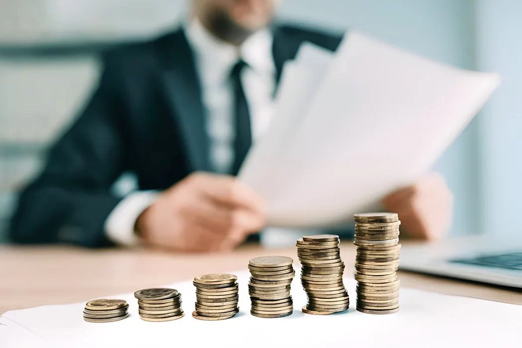 Stacks of coins increasing in height with a professional trustee reviewing documents in the background, symbolizing the financial growth and investment management provided by a corporate trustee in malaysia.