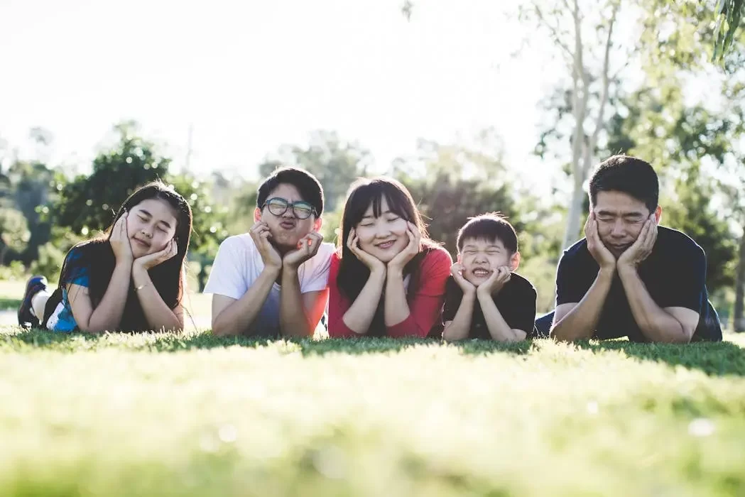 A happy family lying on the grass together, symbolizing that trust services in malaysia are affordable and accessible for everyone, not just the ultra-wealthy.