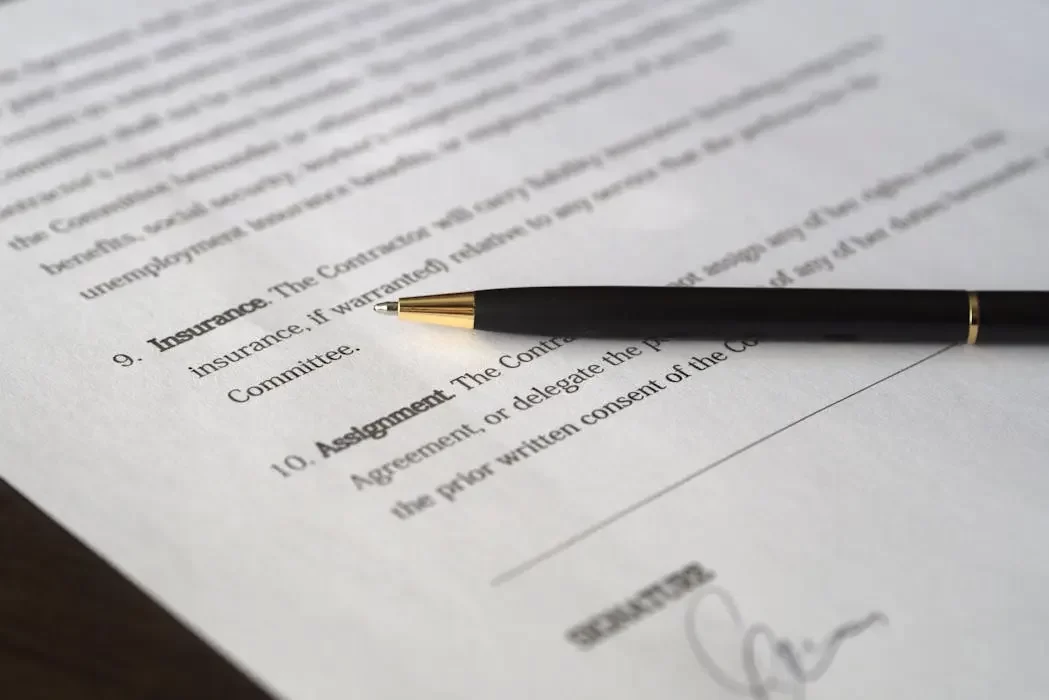 A close-up of a pen resting on a formal insurance agreement document, representing the legal assignment of an insurance policy to a trust in malaysia.