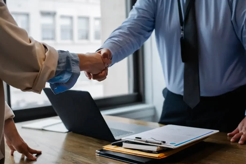 A client and a professional trustee shaking hands over a desk with documents, symbolizing the successful setup and execution of a private trust agreement in malaysia.