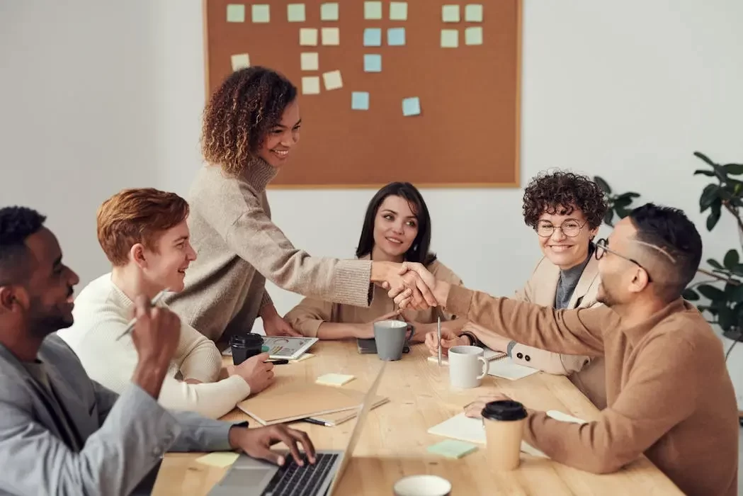 A client shaking hands with a legal professional surrounded by a support team, illustrating the security of hiring a firm over a single individual for will writing.
