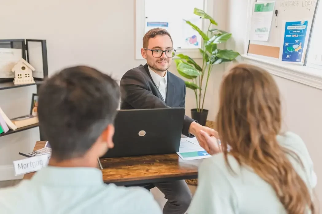 A professional trust advisor shaking hands with a couple at a desk, symbolizing the successful selection and agreement with a trust service provider in malaysia.