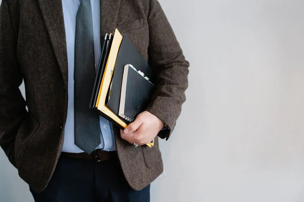 A man in a suit holding a stack of folders and documents, representing the heavy administrative paperwork required for estate probate in malaysia.