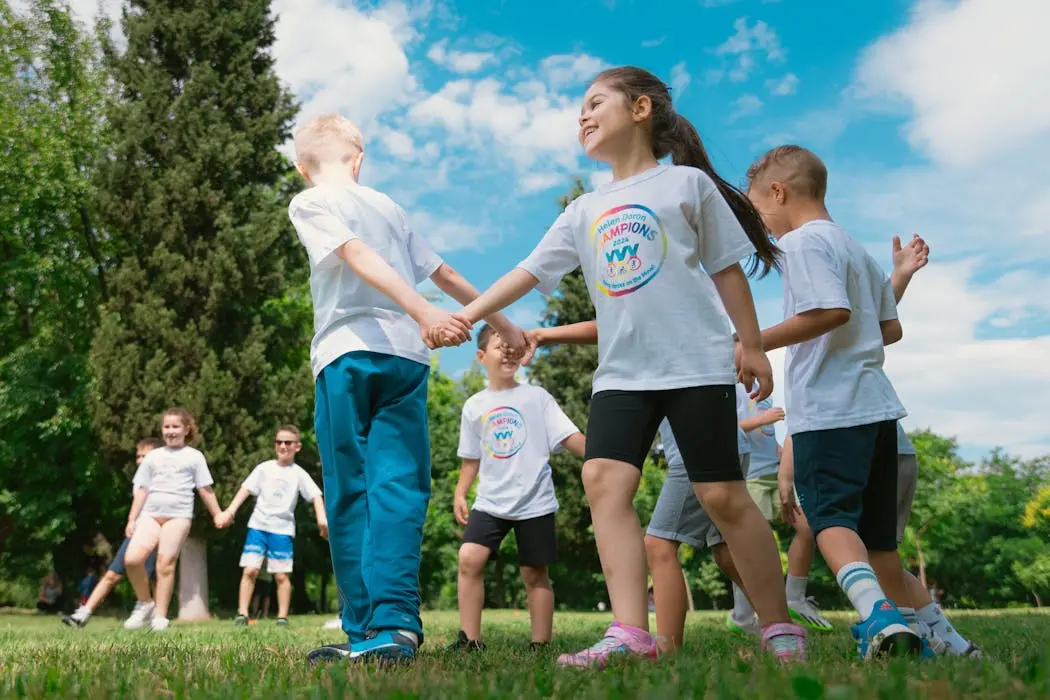 A group of diverse children holding hands in a circle in a sunny park, representing stepchildren in a blended family who need explicit legal protection in an estate plan.